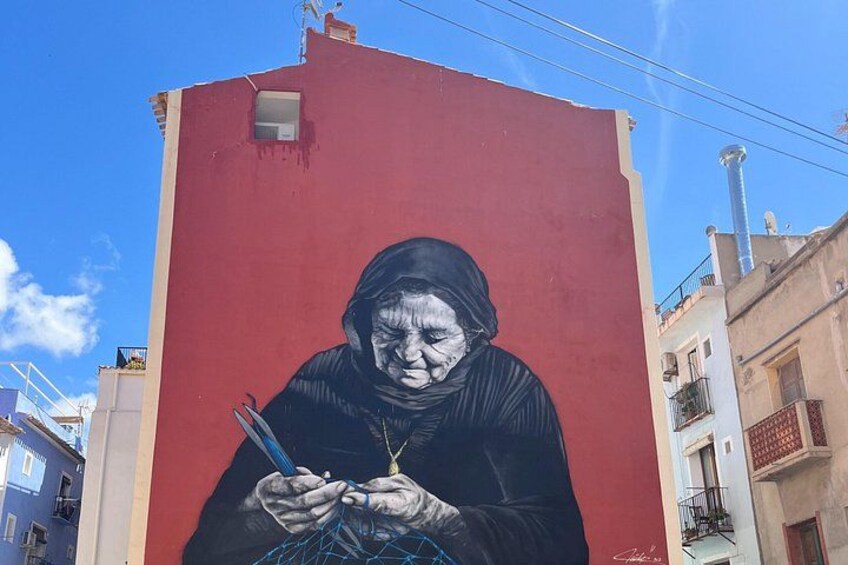 Un murale raffigura una donna anziana su uno sfondo rosso. 2