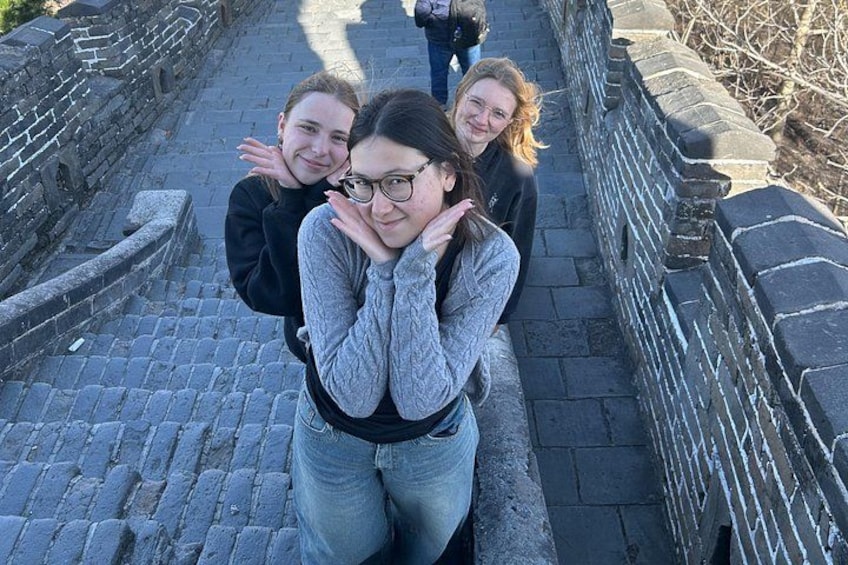 A group of people standing on a stone pathway with a stone wall on one side. 5
