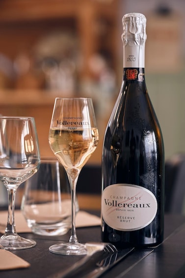 A bottle of Voltaire champagne and two glasses on a table. 3
