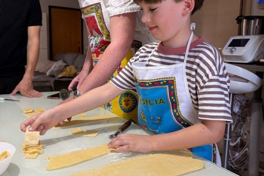 A person preparing food, specifically rolling dough on a table. 2