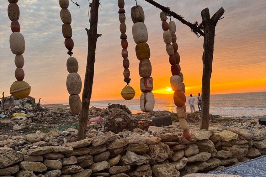 Ein Sonnenuntergang über einem Strand mit Steinmauern und hängenden Objekten. 3