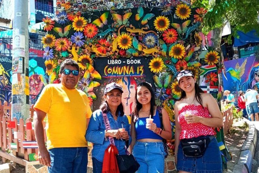 A colorful mural with sunflowers and a sign reading 'LIBRO - BOOK COMUNA 13'. 5
