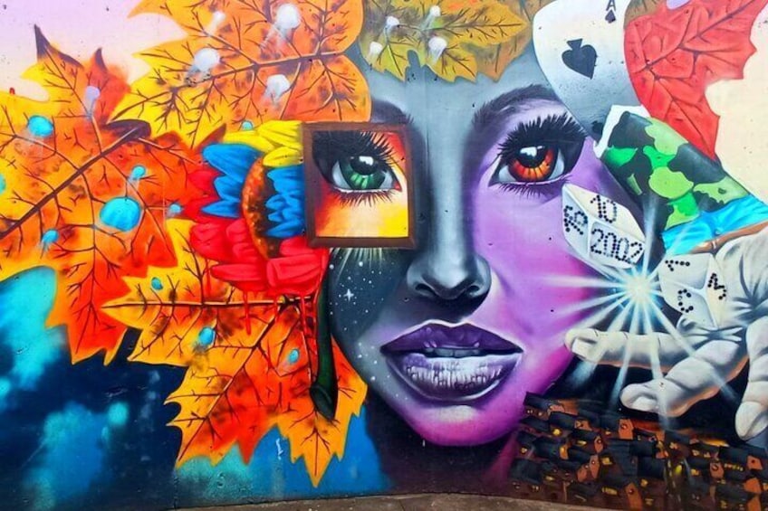 Un murale colorato con foglie autunnali, un volto e un orologio. 1