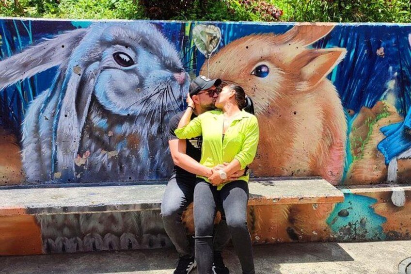 A couple kissing in front of a mural of a rabbit. 4
