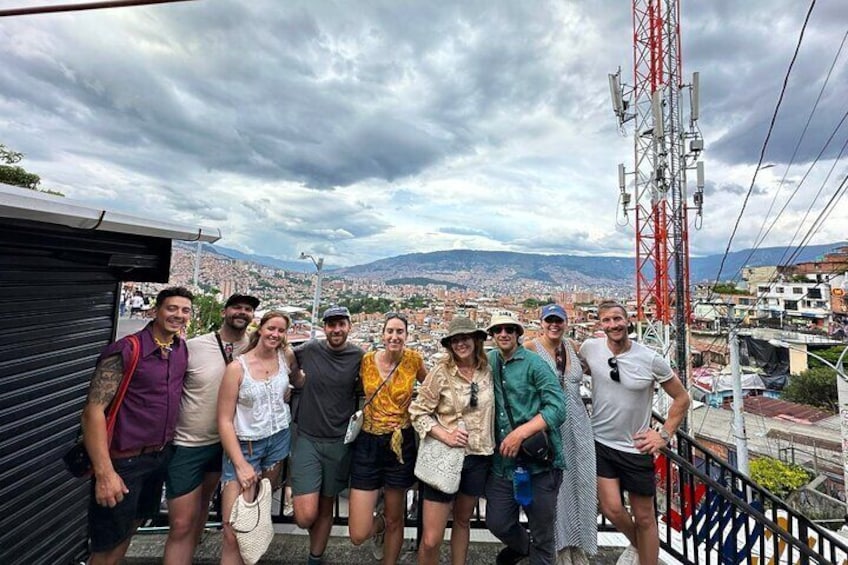 Un gruppo di persone in piedi su un balcone con vista su una città e montagne sullo sfondo. 2