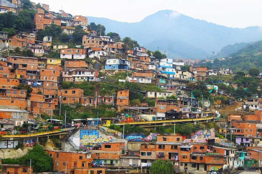 A densely packed hillside settlement with colorful buildings, a winding road, and a mountain in the background. 3