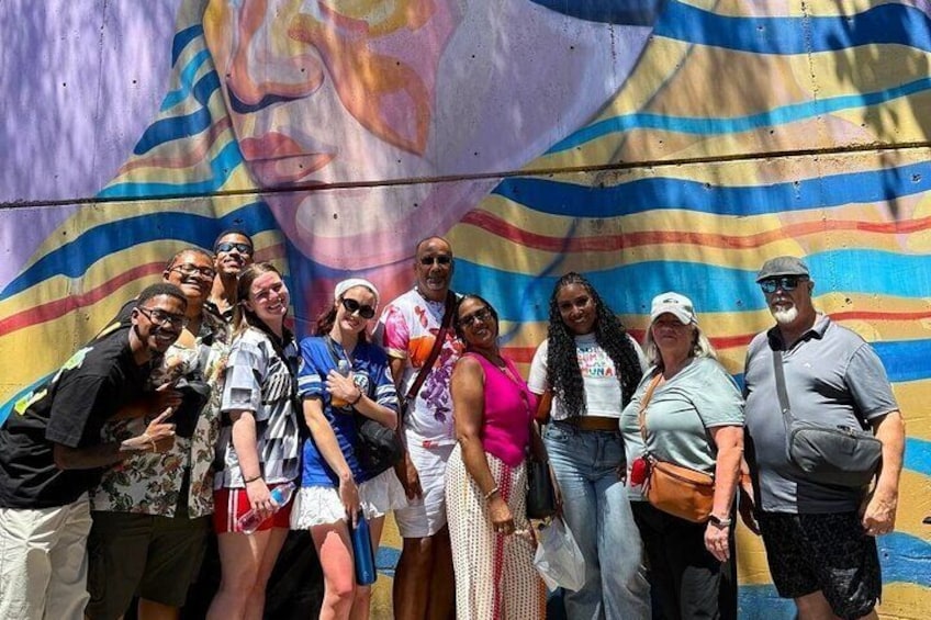 Un gruppo di persone che posa di fronte a un murale colorato. 3