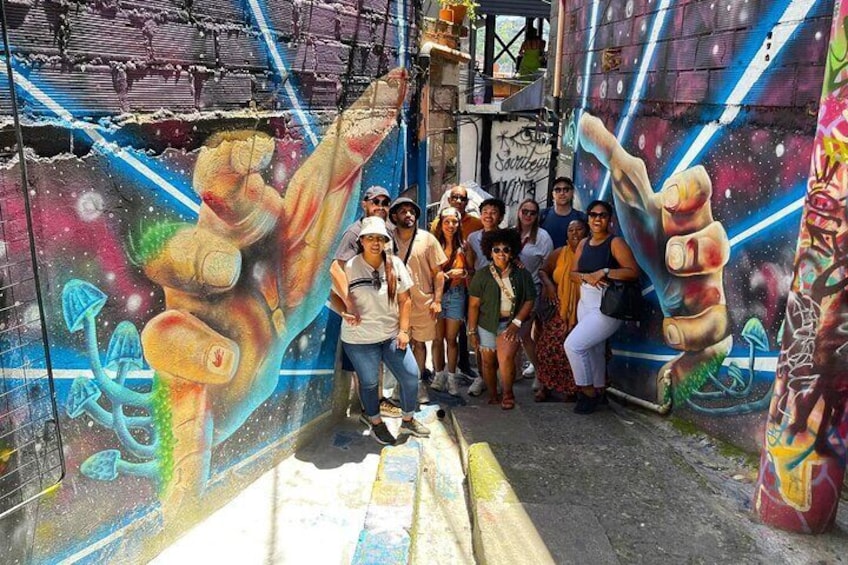 Un gruppo di persone che posa davanti a un murale colorato con motivi astratti e cosmici. 5