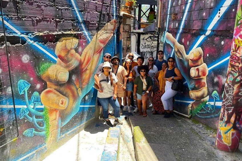 A group of people posing in front of a colorful mural with abstract and cosmic designs. 2