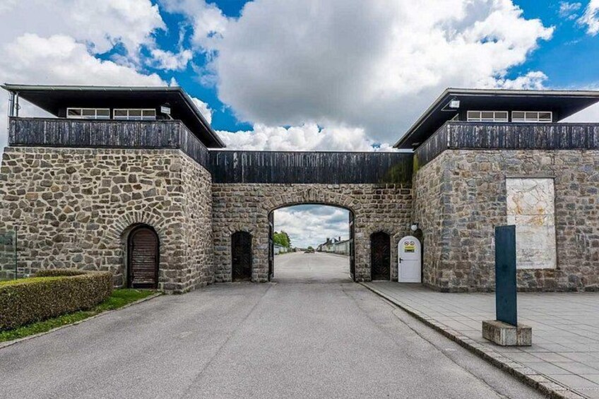 Een stenen boogpoort leidt naar een gebouw met een houten terras. 5