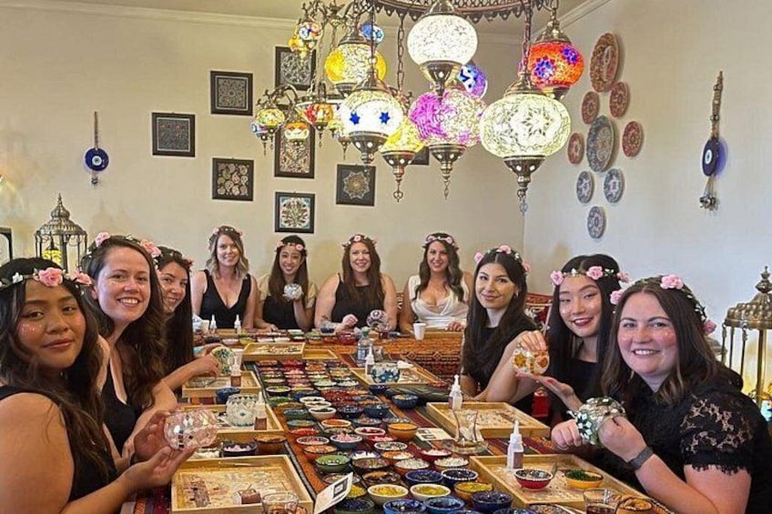A group of people seated around a table with various dishes and a chandelier. 2