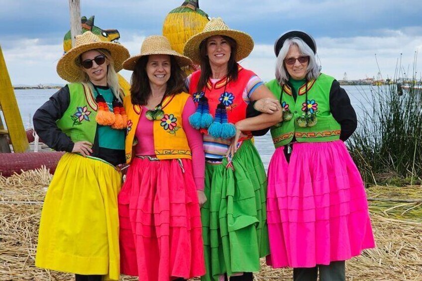 Four people in colorful traditional attire standing by a body of water. 2