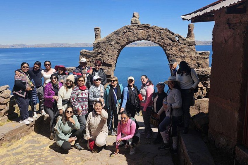 A group of people posing in front of a stone archway with a body of water in the background. 4