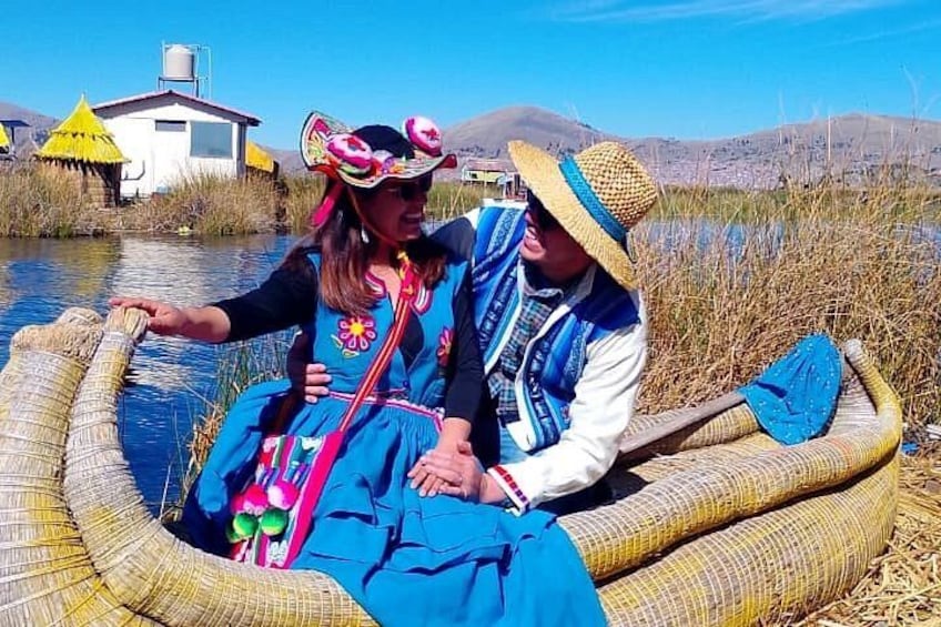 Two people in a traditional boat on a river, surrounded by reeds and a small building in the background. 2