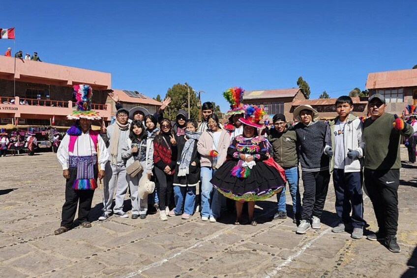 A group of people in traditional attire posing for a photo in an outdoor setting with buildings in the background. 2