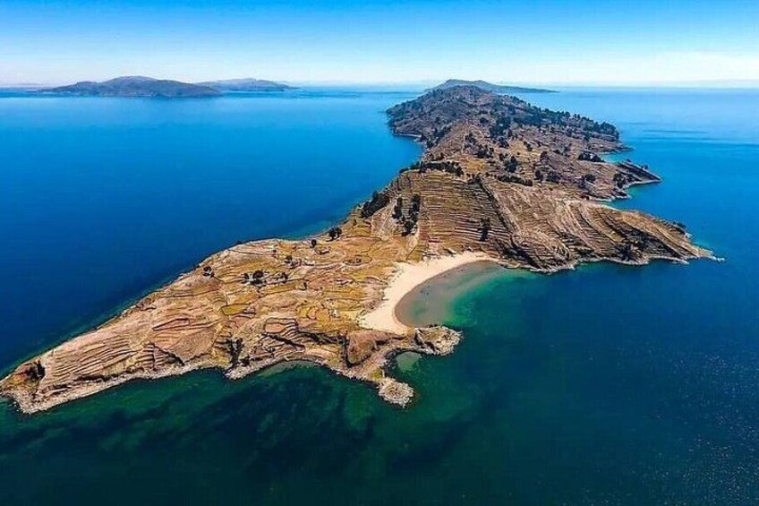 Ett flygbildsbild av ett kustlandskap med en framträdande halvö, en strand och klart blått vatten. 3