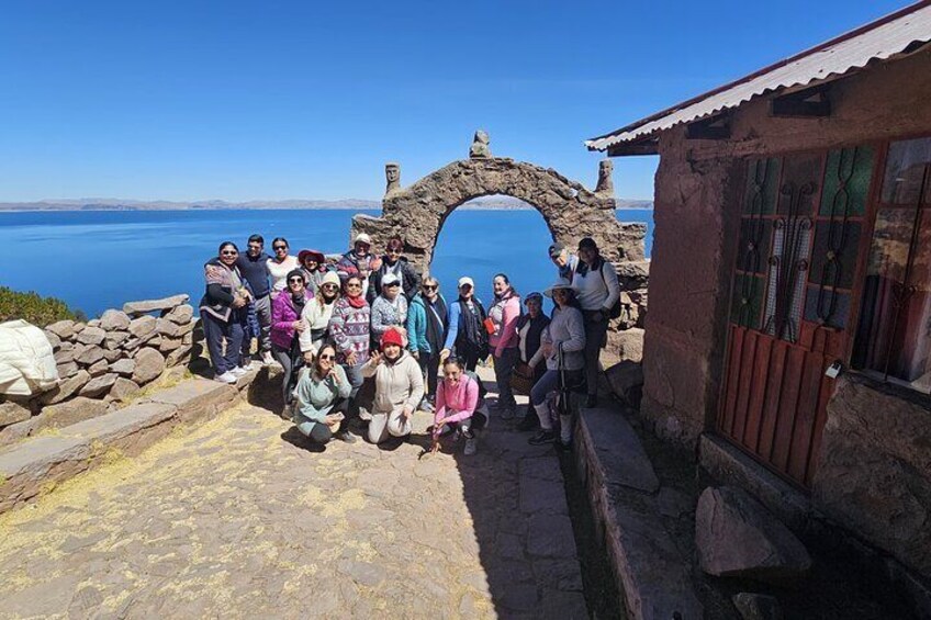 Un grupo de personas en un mirador panorámico, con un arco de piedra y un edificio con tejado rojo. 3