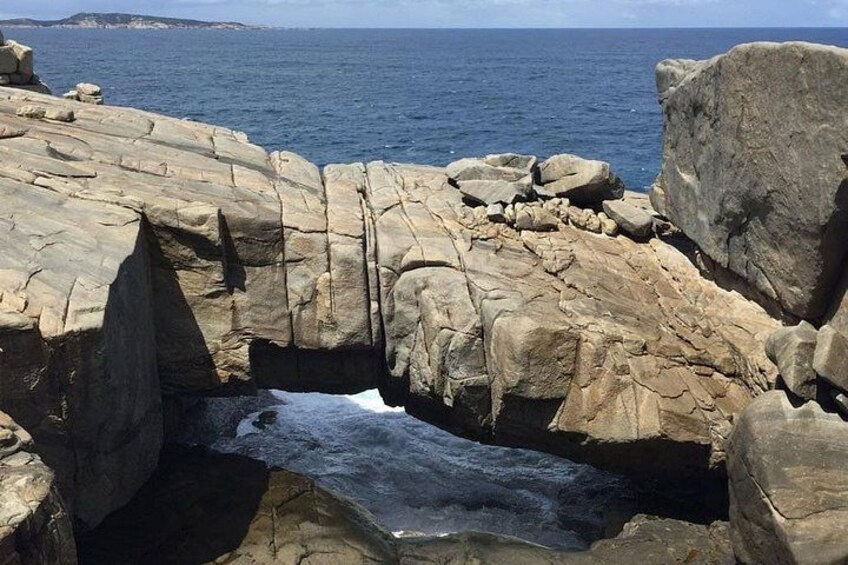 A coastal rock formation with a natural archway and a narrow water passage. 2