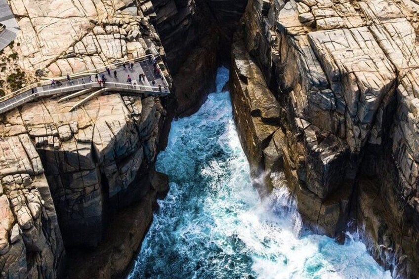 A rocky coastal landscape with a narrow waterway and a pedestrian bridge. 1