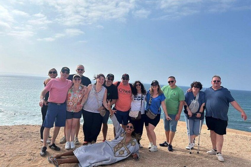 En gruppe mennesker på en sandstrand med oceanen i baggrunden. 4