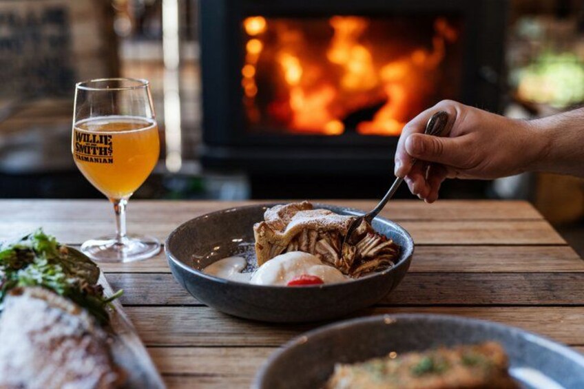A person eating a meal with a bowl and a glass of beer, with a fireplace in the background. 3