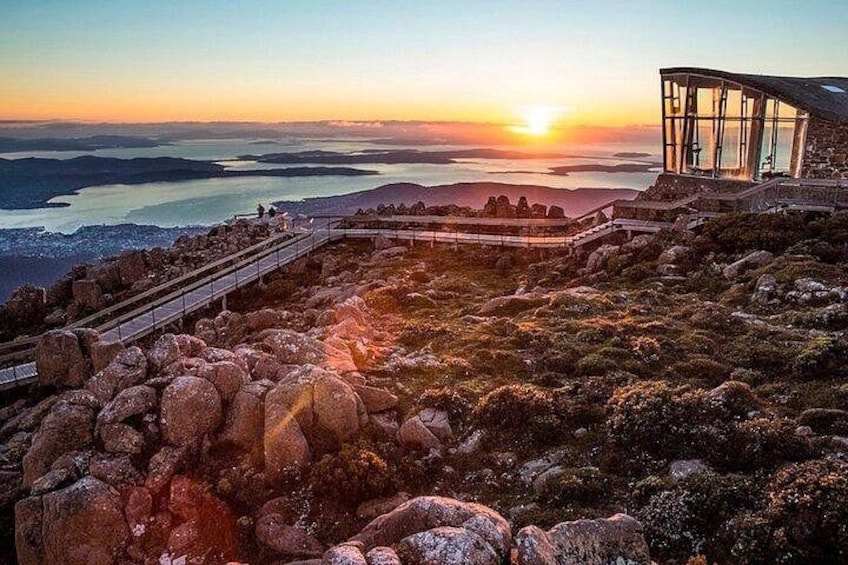 A sunset view from a rocky outcrop with a glass structure on the right. 2