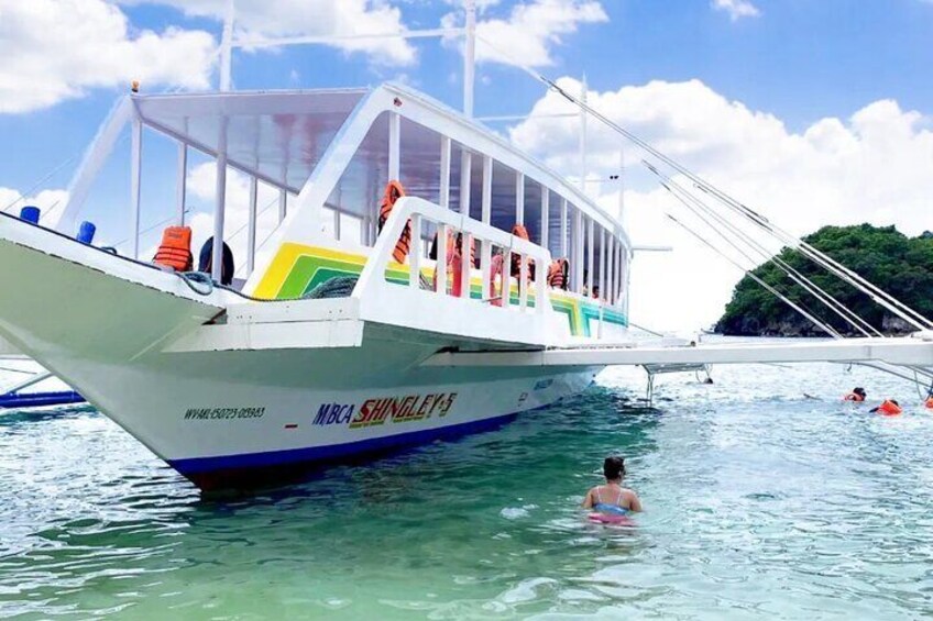 Un bateau nommé « MBC SHINGLETON » avec des personnes à bord, et une personne nageant à proximité. 1