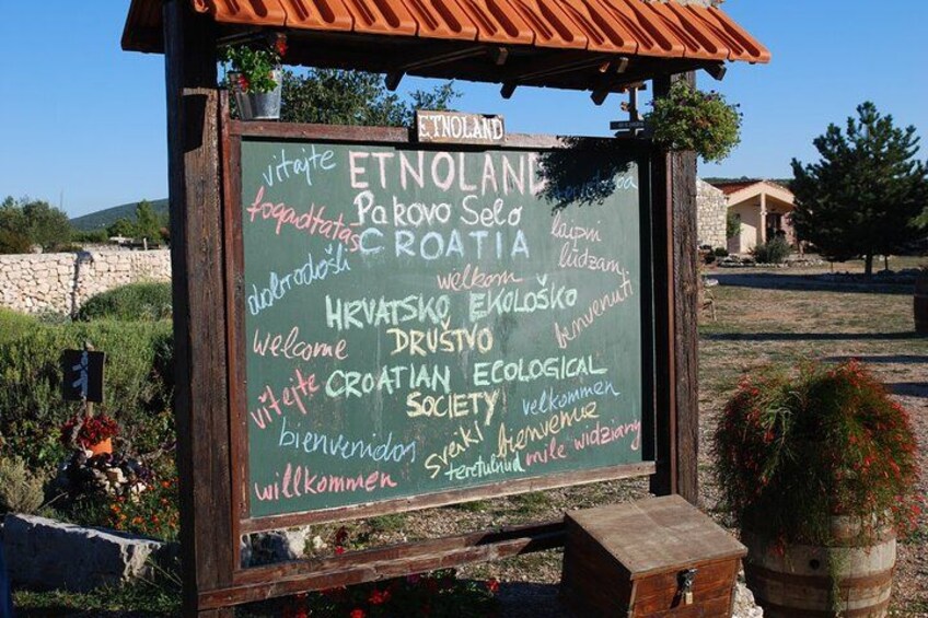 A signboard with greetings in multiple languages welcoming visitors to a Croatian ecological society. 2