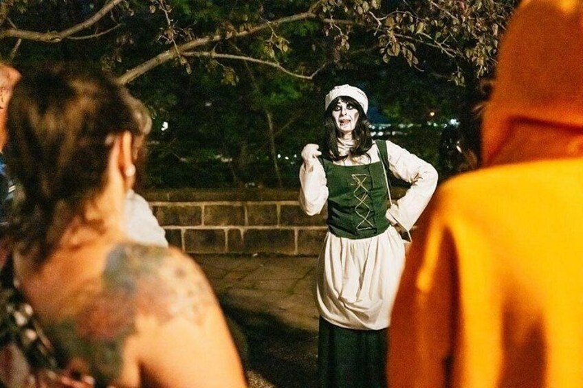 Una persona vestida con traje de época parada al aire libre de noche. 3
