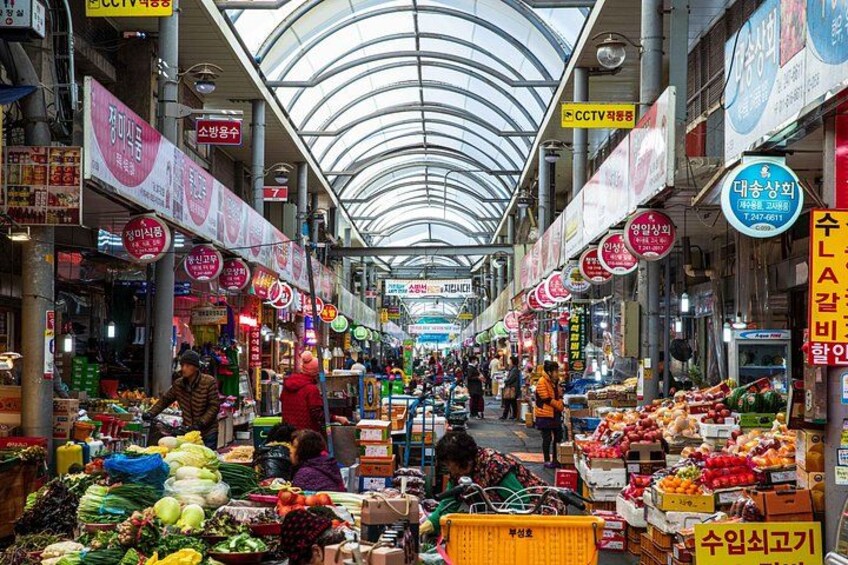 A busy indoor market with various stalls selling fruits, vegetables, and other goods. 5