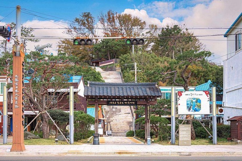 A traditional Japanese gate, a street with a traffic light, and a signboard. 3