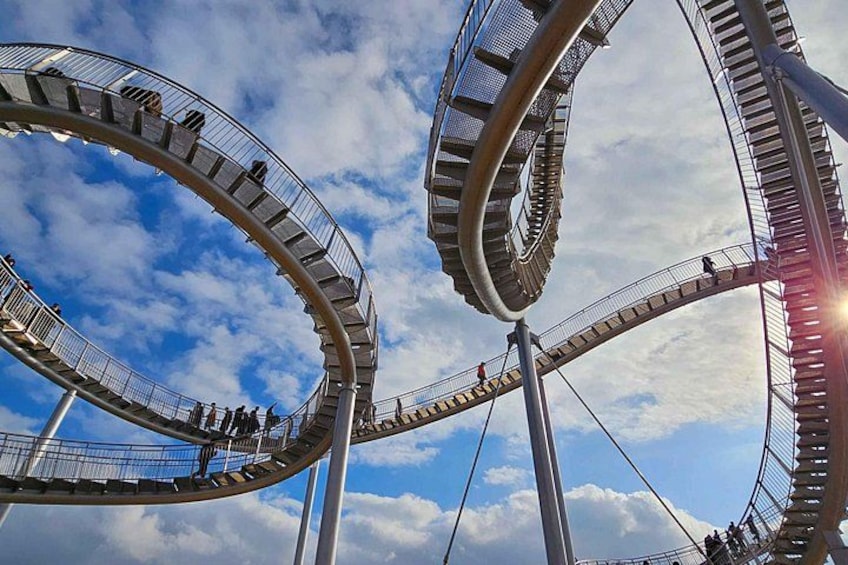 A roller coaster with multiple loops against a blue sky with clouds. 2