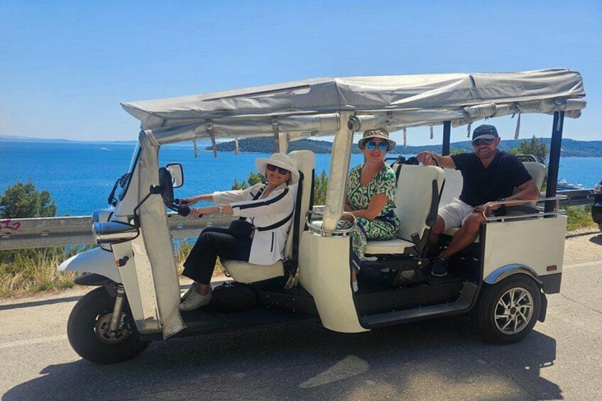 A golf cart on a road with a coastal view. 1