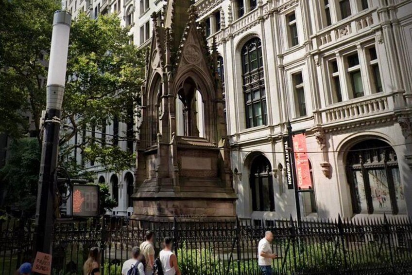 Un edificio histórico con arquitectura intrincada, una cerca de metal negro y personas caminando. 5