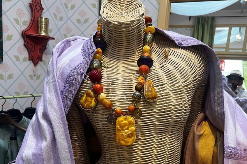 Un maniquí con un detalle tejido similar a una cesta y un colorido collar de cuentas. 3