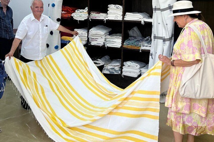 A store with folded towels and a striped towel being held. 2