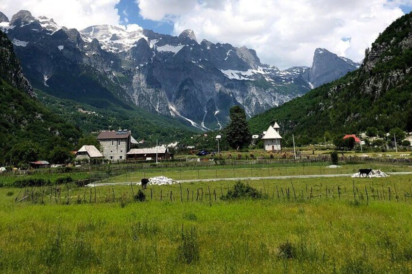 A rural village with houses, a field, and mountains in the background. 3