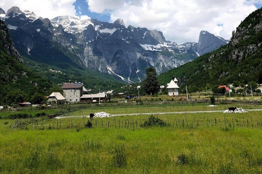 En lantlig by med hus, en åker och berg i bakgrunden. 2