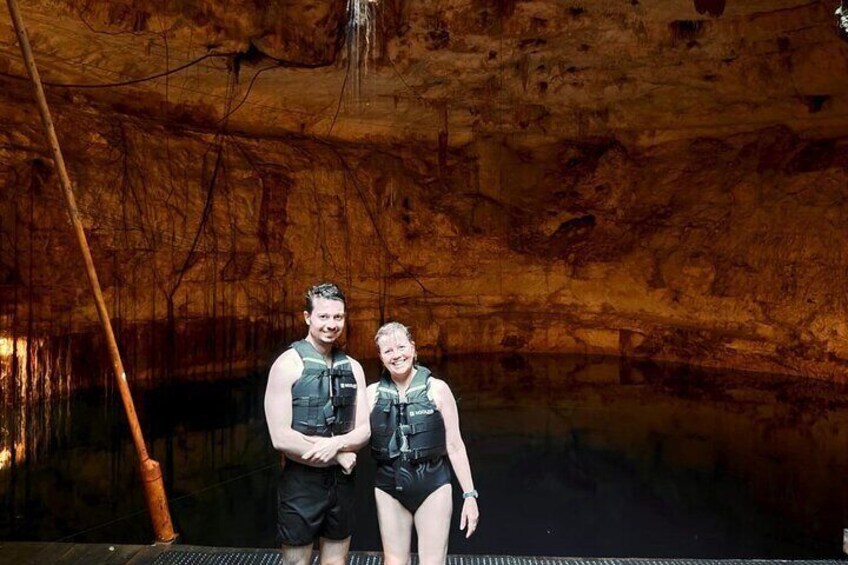 Two people standing in a cave with a wooden ladder and a metal grate. 4