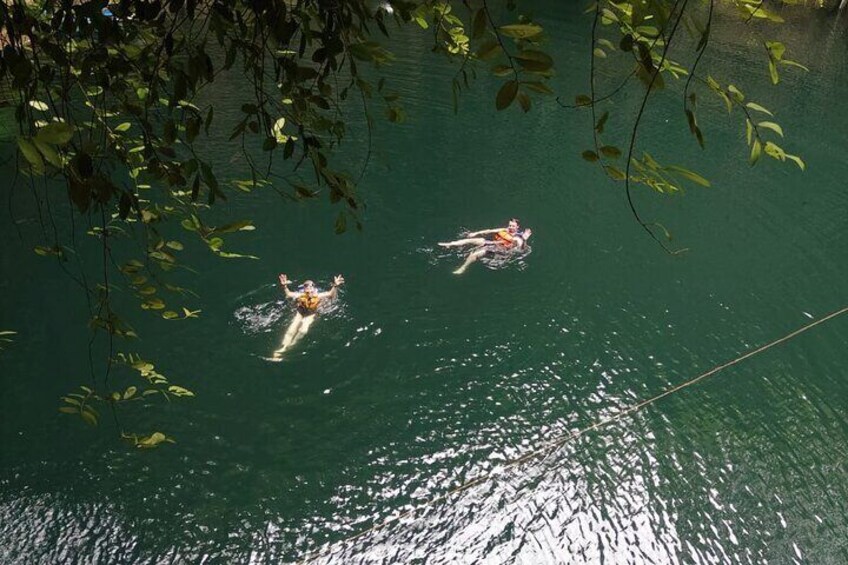Two people swimming in a body of water surrounded by trees. 5