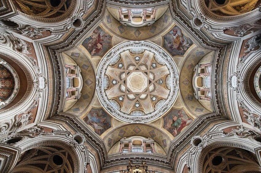 A detailed view of an ornate ceiling with geometric patterns and frescoes. 3