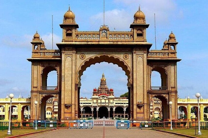 A large, ornate archway with intricate carvings and domes, leading to a building with a red roof. 2