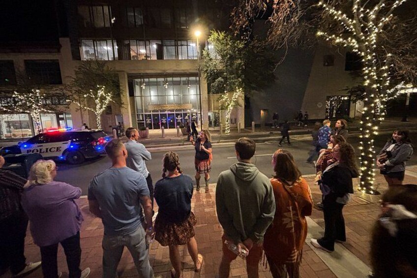 A nighttime street scene with a police car, pedestrians, and illuminated trees. 4