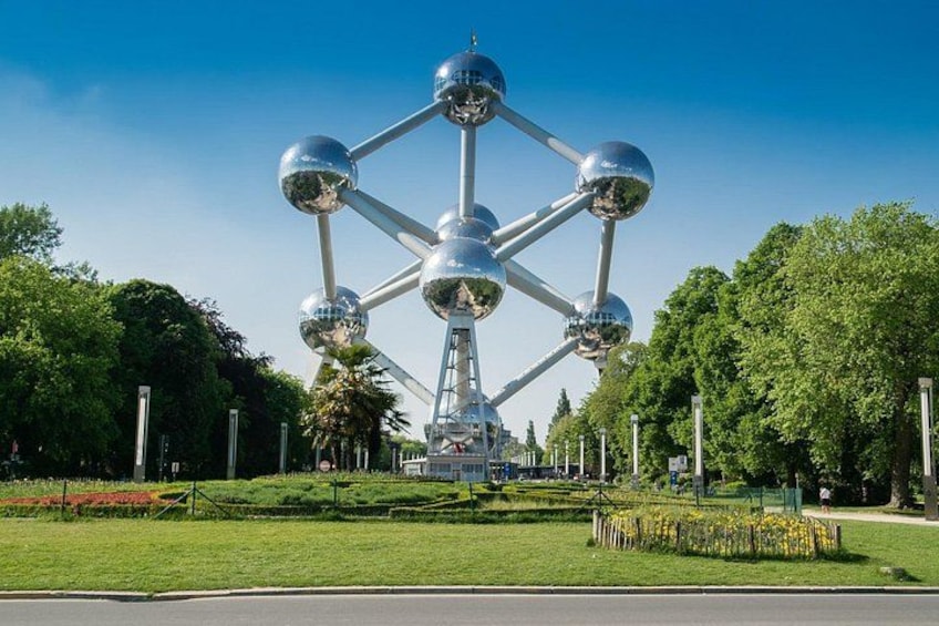 Eine große Metallkonstruktion mit sphärischen Elementen, umgeben von einem Park mit Gras und Bäumen. 5