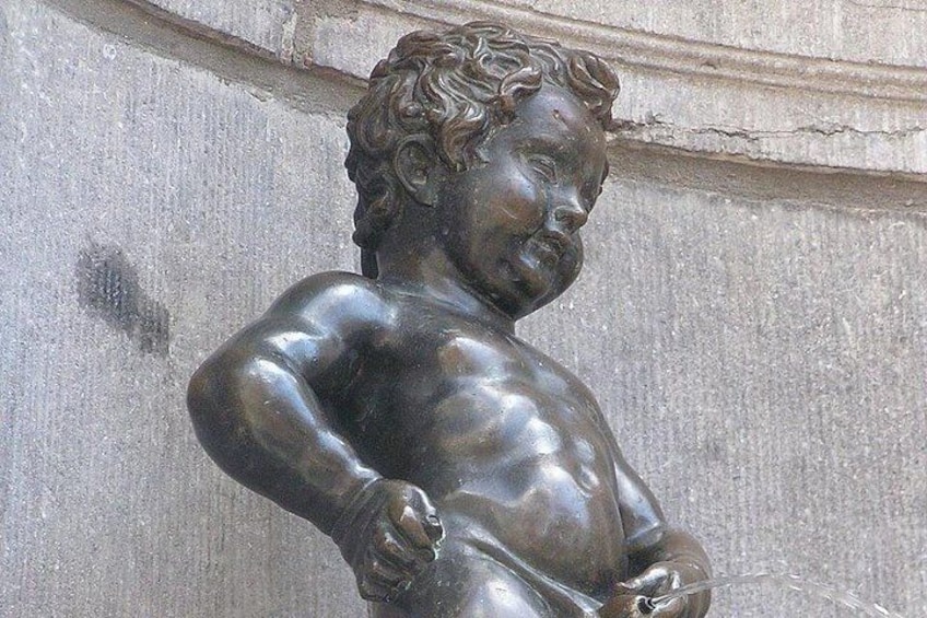 Eine bronzene Statue einer muskulösen Figur mit lockigem Haar, die an einer Steinmauer steht. 3