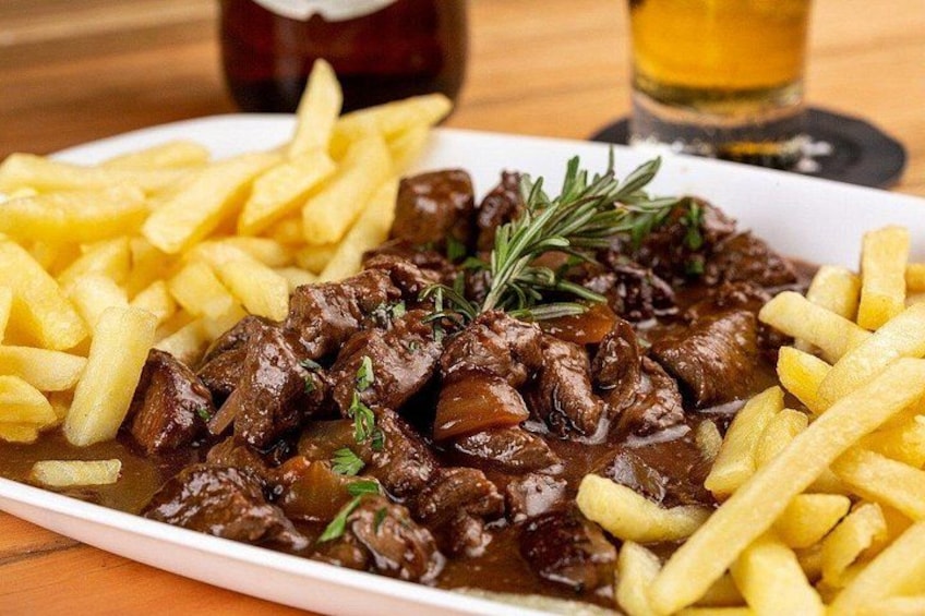 A plate of beef stew with gravy and French fries. 2