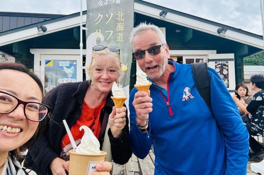 Trois personnes, chacune tenant une glace à la main et une tasse de café, se tiennent devant un bâtiment sur lequel est affiché un panneau indiquant « ouvert ». 3