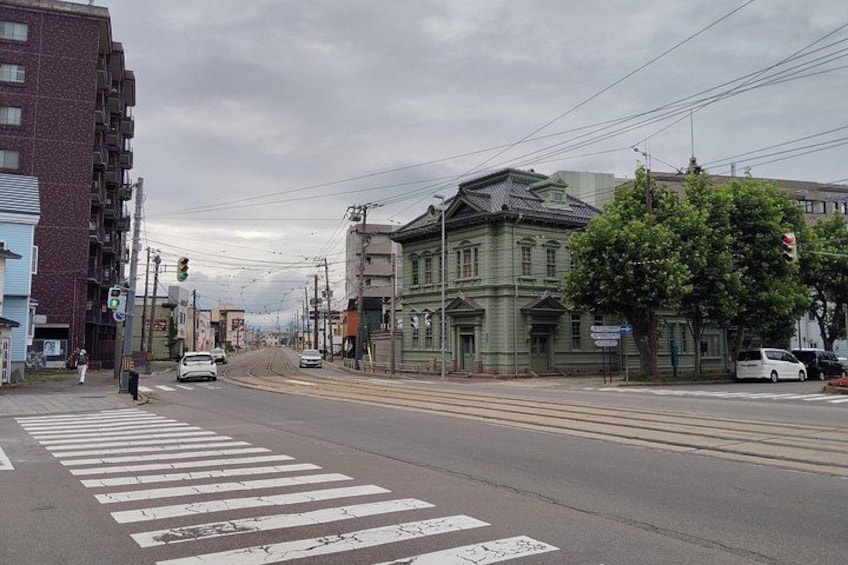 A street with buildings, a pedestrian crossing, and vehicles. 3