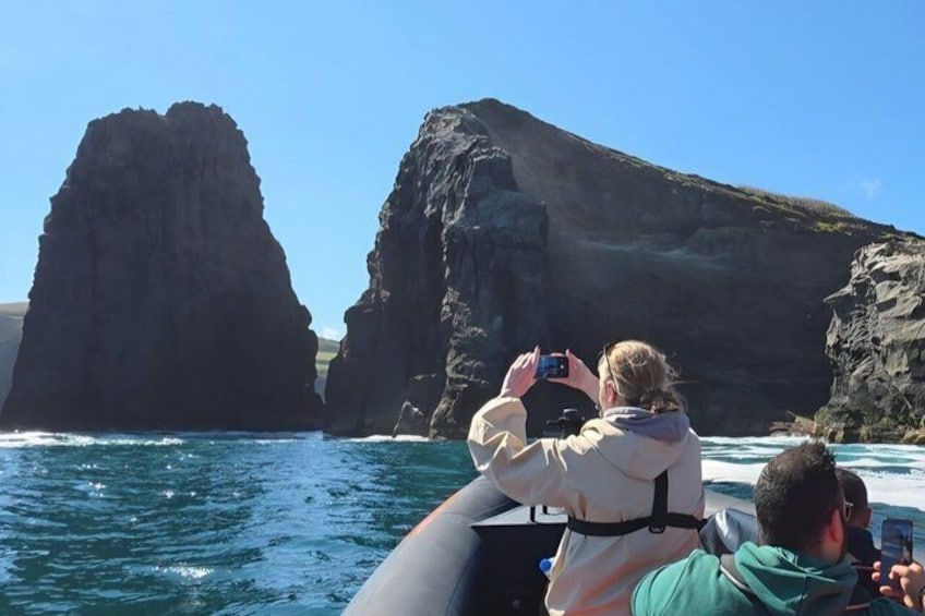 Una embarcación con dos personas fotografiando un escarpado litoral. 4