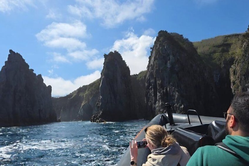 Un barco navegando entre acantilados rocosos mientras pasajeros contemplan el paisaje. 5